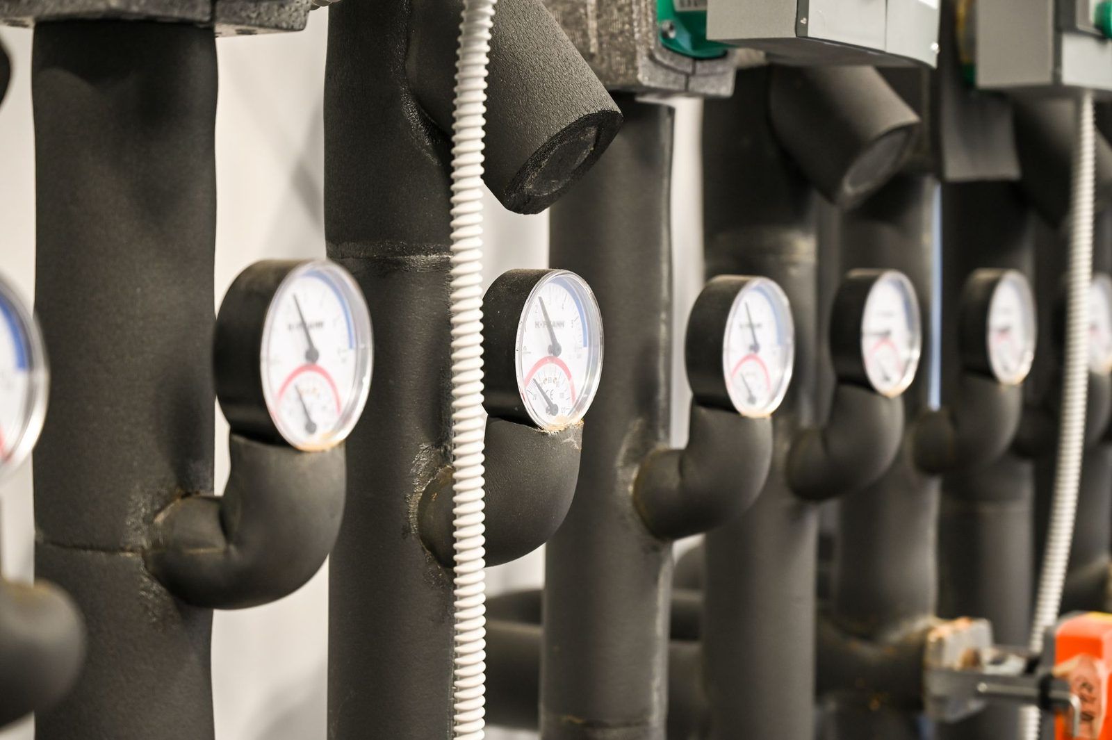 Manometer an gedämmten Rohren im Heizraum